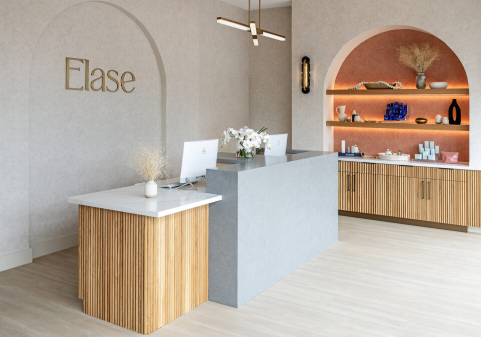 Elase Sarasota laser hair removal and medical spa reception desk with arched entryway, gold logo, and warm neutral interior design