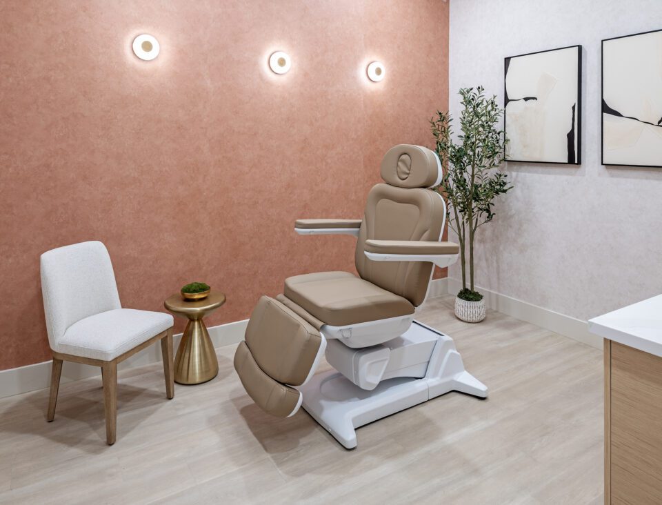 Elase Sarasota treatment room with adjustable medical spa chair, terracotta accent wall, and modern gold sconce lighting