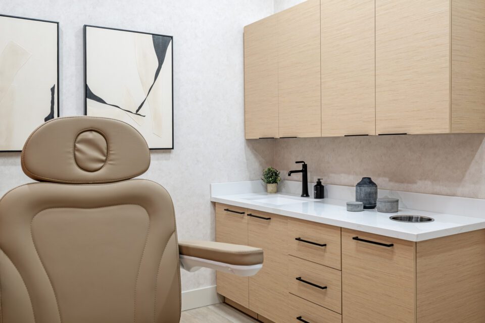lase Sarasota med spa treatment room with light wood cabinetry, white quartz countertop, black fixtures, and abstract wall art